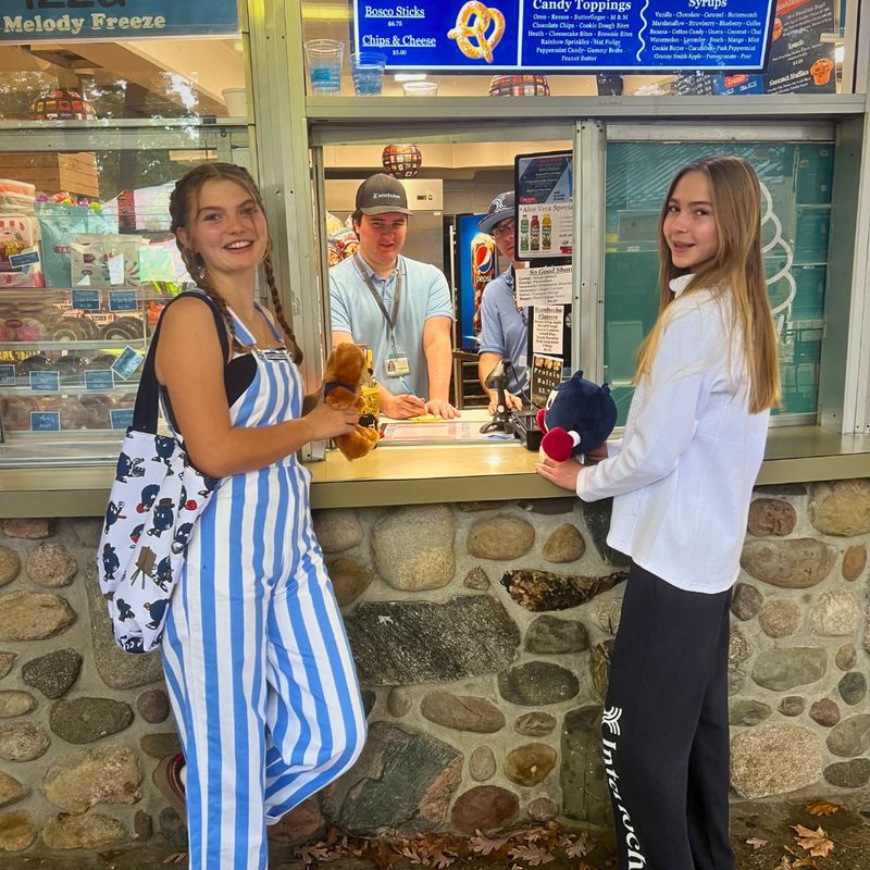 Two people standing in front of a ice cream shop with a stone wall background