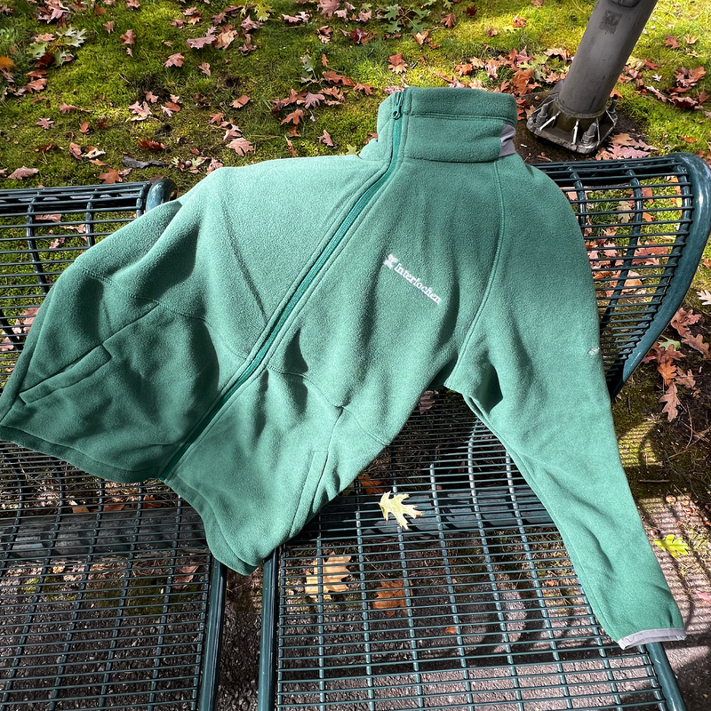 Green fleece jacket on a metal chair with fallen leaves in the background