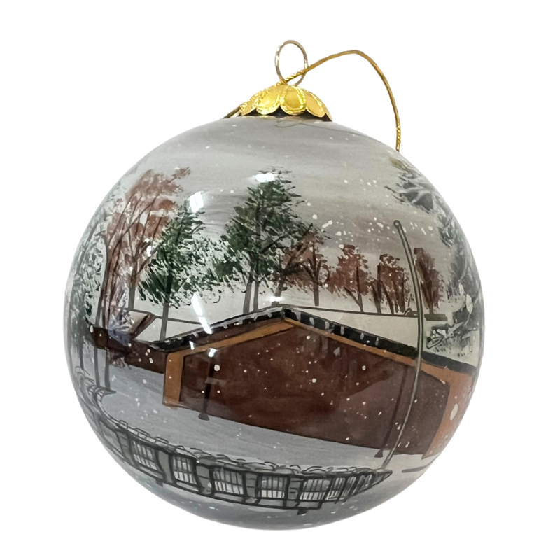 Hand Painted Glass ornament with a winter scene of a cabin and trees on a white background