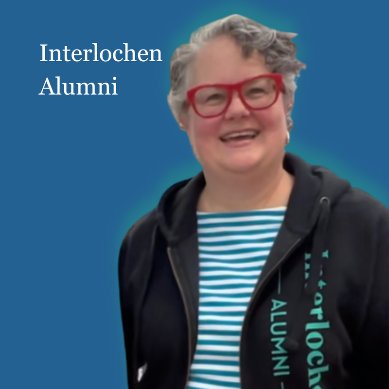 Person wearing a black Interlochen Alumni jacket with a blue background