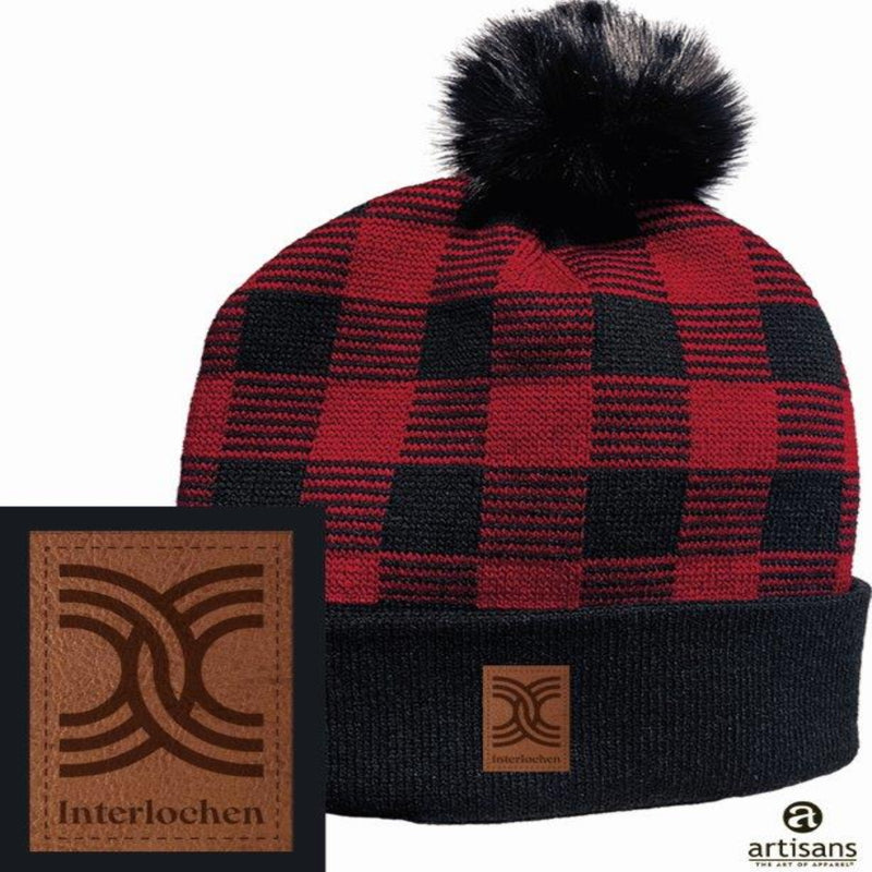 A black and red checkered beanie with a soft pom-pom on top, featuring an Interlochen logo leather-like patch on the brim.