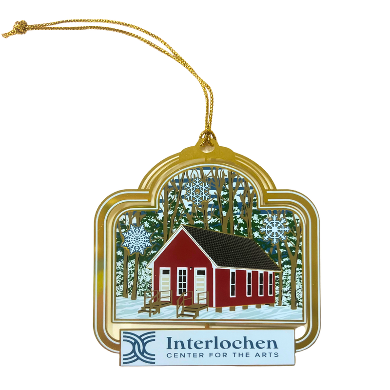 Decorative ornament with a red cabin in a snowy forest and 'Interlochen Center for the Arts' logo.